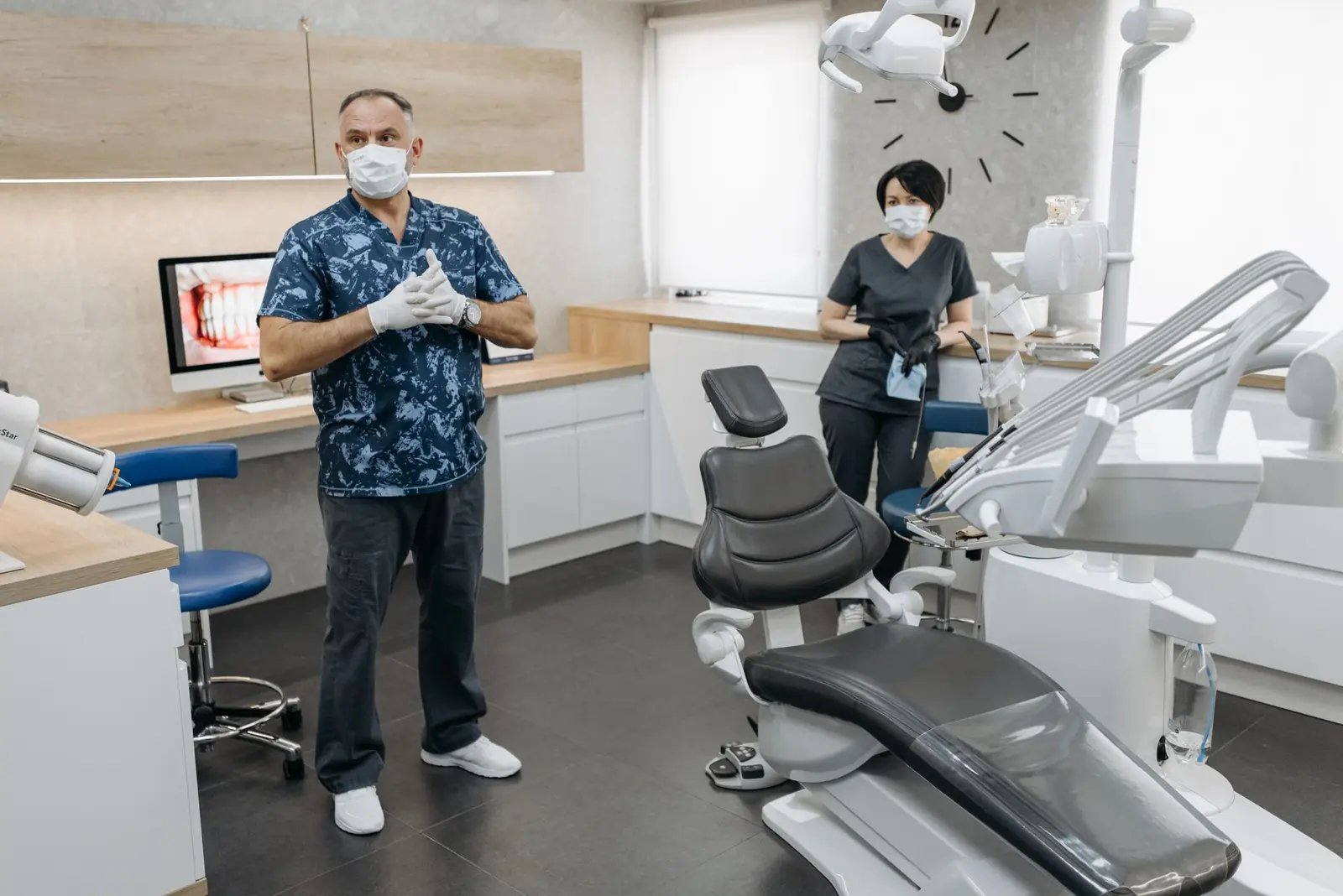 Echipa clinicii discutând cu un pacient lângă unitul dentar